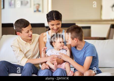 Famille multiraciale à la maison. Mère avec ses fils adoptifs. Jeune mère de race mixte se détendant avec ses enfants. Détente en famille variée Banque D'Images