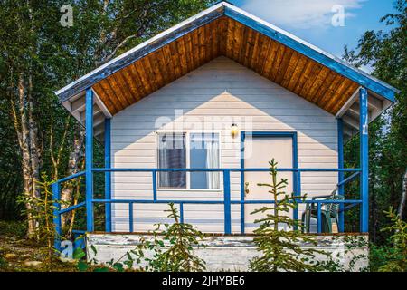 Petite maison dans les bois de l'Alaska - porche avec rails et parement blanc trimed en bleu clair Banque D'Images