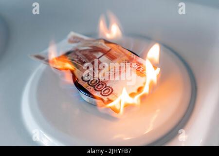 Le rouble russe brûle dans le feu. Concept la hausse du prix du gaz en Russie. Une facture de 5000 roubles brûle dans un feu sur un poêle à gaz. Cher Banque D'Images