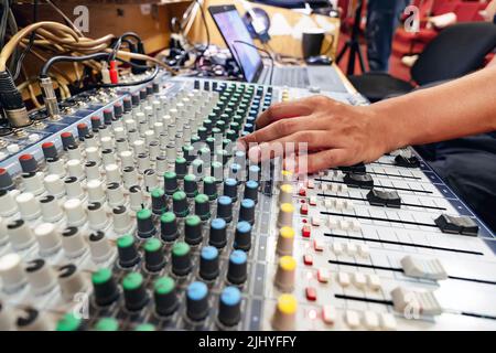 La main mâle règle la balance sur la station de travail Digital Sound à côté du routeur et du bureau Banque D'Images