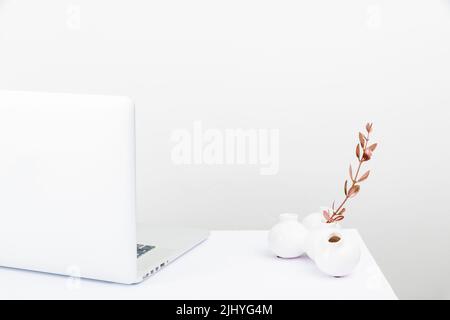 Un espace de travail bien rangé avec un ordinateur portable blanc Banque D'Images
