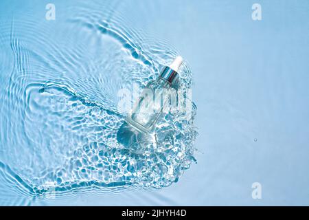 Produit cosmétique hydratant, sérum, en flacon transparent dans les vagues d'eau Banque D'Images