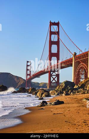 Vagues sur la plage à côté du Golden Gate Bridge au coucher du soleil Banque D'Images