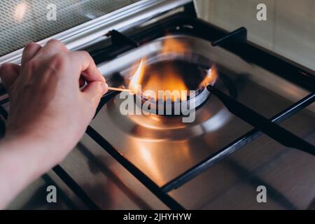 Une main de femme avec allumettes feux cuisinière à gaz dans son appartement. Banque D'Images