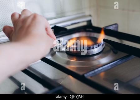 Une main de femme avec allumettes feux cuisinière à gaz dans son appartement. Banque D'Images