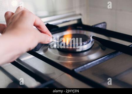 Une main de femme avec allumettes feux cuisinière à gaz dans son appartement. Banque D'Images