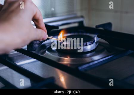 Une main de femme avec allumettes feux cuisinière à gaz dans son appartement. Banque D'Images