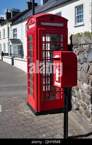 Glenarm, Royaume-Uni- 29 mai 2022: Un téléphone rouge britannique et une boîte postale dans une rue à Glenarm Banque D'Images