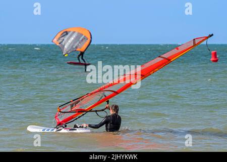 Planche à voile femelle entrant dans l'eau et wingboarder / bord d'aile sur planche à voile / planche hydroptère surf avec aile gonflable sur la mer du Nord Banque D'Images