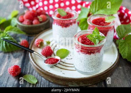 Petit déjeuner sain. Pots en verre avec pudding au chia à la framboise et à la confiture ou smoothies aux graines de chia sur table rustique. Banque D'Images
