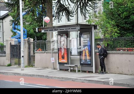 Un homme s'arrête à un arrêt de bus, attendant un bus, Cork. Irlande. Banque D'Images