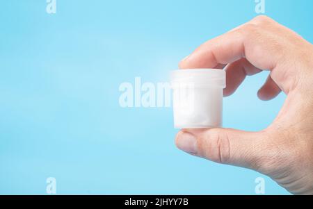 don de sperme concept, un tube à essai avec un liquide blanc dans l'espace de copie à la main sur un fond bleu. Banque D'Images