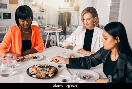 La nourriture rassemble les gens. Un groupe d'amis de sexe féminin qui déguste des sushis. Banque D'Images