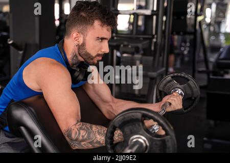 Beau homme avec des tatouages dans son entraînement de 20s dans la salle de gym Banque D'Images