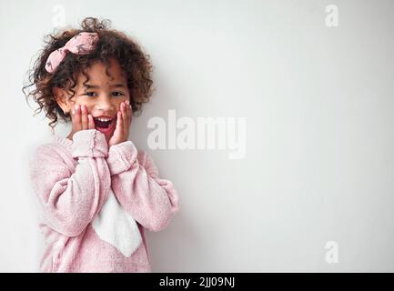 Elle rend la journée plus lumineuse. Une adorable petite fille qui semble surprise sur fond gris. Banque D'Images