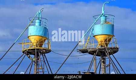 peu de grands bunker de bac à céréales de couleur (distributeur et sèche-linge) derrière les fils à l'ascenseur dans le ciel bleu par temps ensoleillé, la diversité de la technologie moderne Banque D'Images