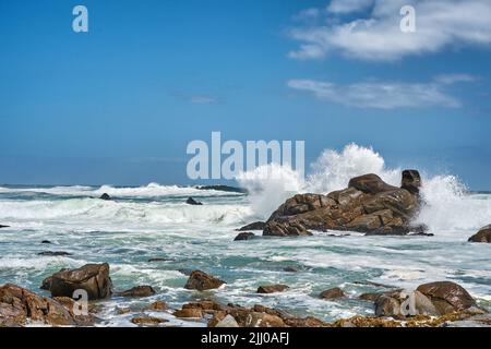 De grandes vagues éclaboussant et se brisant sur la côte. Mer turbulent avec des marées rugueuses provenant de vents forts qui s'écrasant sur des rochers de plage avec un ciel bleu Banque D'Images