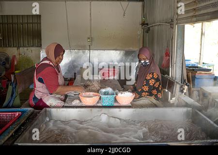 Terengganu, Malaisie: 16 janvier 2022 - deux femmes faisant le célèbre kérapok lekor ou saucisse de poisson Banque D'Images