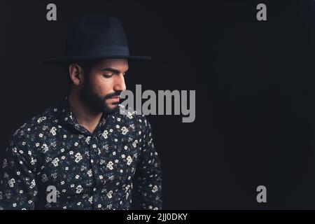 Barbu latino-américain beau homme personne touchant chapeau noir regardant sévèrement dans l'espace de copie de l'appareil photo fond noir studio tourné de gros plan moyen. Photo de haute qualité Banque D'Images