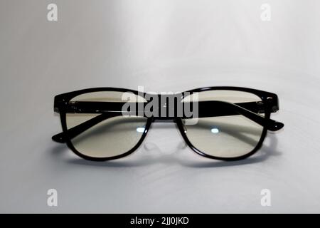 Flou artistique des lunettes noires sur fond blanc. Flat lay, vue de dessus. Une paire de lunettes à rebord foncé vues de l'avant, avec les temples ouverts. Myopie. Banque D'Images