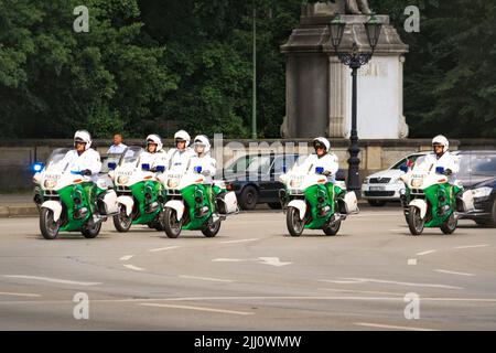 Vue des policiers portant un casque sur une promenade en moto blanche verte en convoi de voitures VIP à Victory Column, Tiergarten en été avec des arbres en arrière-plan. Banque D'Images