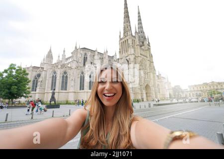 Femme de grande humeur prend photo selfie devant la cathédrale de Bordeaux, France Banque D'Images