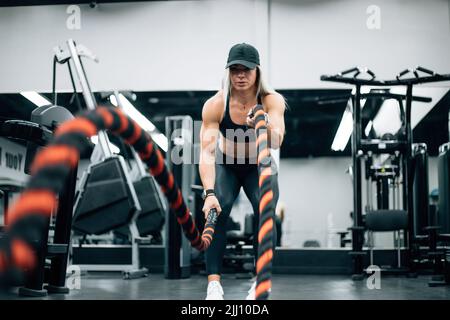 FIT femme avec des cheveux blonds faire l'entraînement de corde dans la salle de gym Banque D'Images