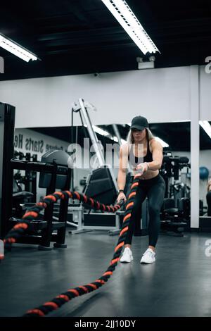 FIT femme avec des cheveux blonds faire l'entraînement de corde dans la salle de gym Banque D'Images