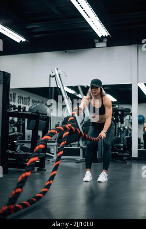 FIT femme avec des cheveux blonds faire l'entraînement de corde dans la salle de gym Banque D'Images
