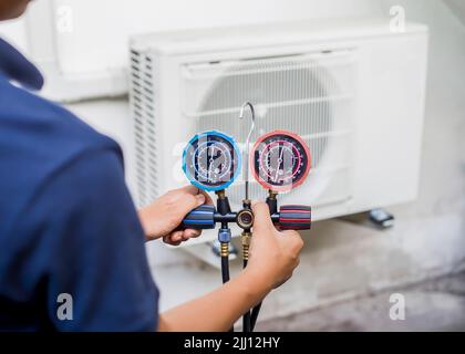 Mécanicien de réparation de l'air utilisant des équipements de mesure pour remplir les climatiseurs industriels d'usine. Banque D'Images