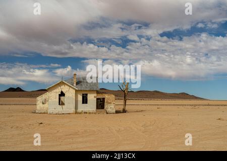 Un ancien bâtiment abandonné en Namibie dans le désert du Namib près de Garub. Journée ensoleillée avec de grands nuages blancs. Banque D'Images