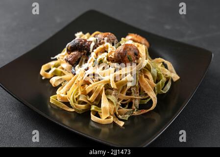 pâtes alfredo aux champignons dans une sauce à la crème sur une assiette noire sur fond sombre. Plat de pâtes italien traditionnel fettuccini Banque D'Images