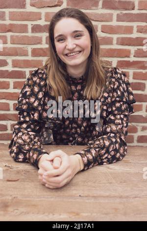 Gros plan prise de vue d'un jeune garçon aux cheveux bruns souriant, sur fond de brique rouge avec espace de copie. Photo de haute qualité Banque D'Images