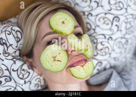 Jeune belle femme avec un paquet de visage et des tranches de concombre frais sur ses yeux. Masque de boue maison à la maison. Multani sol visage-pack, or visage Banque D'Images