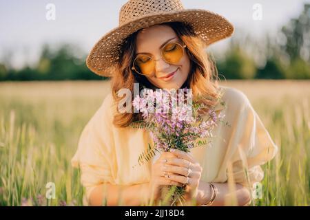 Portrait d'une femme heureuse en chapeau de paille dans un champ de blé vert frais. Arrière-plan herbe. Nature incroyable, terres agricoles, culture de céréales. Femme élégante avec Banque D'Images