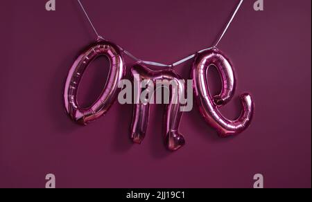 Un ballon métallique de 1 mots sur le fond violet de la paroi. Banque D'Images