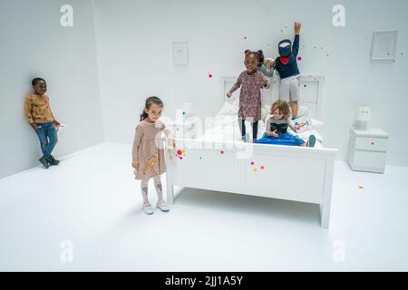 Les enfants appliquent les premiers autocollants au travail interactif de Yayoi Kusama la salle d'oblitération du Tate Modern à Londres, qui commence comme un appartement blanc vierge rempli de tout mobilier blanc. Les visiteurs reçoivent une feuille d'autocollants colorés à leur entrée pour transformer l'installation en une mer de couleur. Date de la photo: Vendredi 22 juillet 2022. Banque D'Images