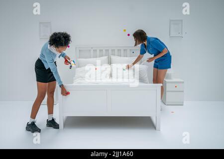 Deux visiteurs au Tate Modern à Londres, appliquez les premiers autocollants au travail interactif de Yayoi Kusama la salle d'obliteration, qui commence comme un appartement blanc vierge rempli de tout mobilier blanc. Les visiteurs reçoivent une feuille d'autocollants colorés à leur entrée pour transformer l'installation en une mer de couleur. Date de la photo: Vendredi 22 juillet 2022. Banque D'Images