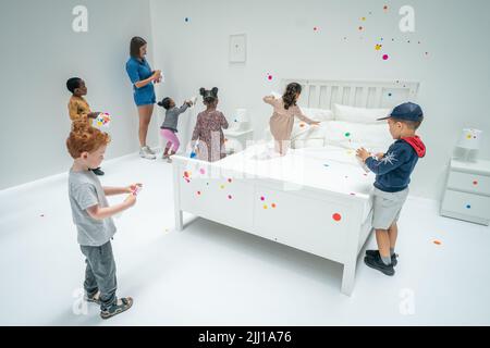 Les enfants appliquent les premiers autocollants au travail interactif de Yayoi Kusama la salle d'oblitération du Tate Modern à Londres, qui commence comme un appartement blanc vierge rempli de tout mobilier blanc. Les visiteurs reçoivent une feuille d'autocollants colorés à leur entrée pour transformer l'installation en une mer de couleur. Date de la photo: Vendredi 22 juillet 2022. Banque D'Images