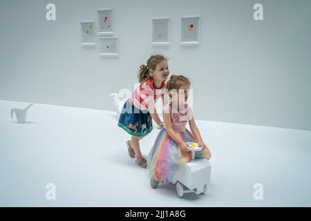 Les enfants appliquent les premiers autocollants au travail interactif de Yayoi Kusama la salle d'oblitération du Tate Modern à Londres, qui commence comme un appartement blanc vierge rempli de tout mobilier blanc. Les visiteurs reçoivent une feuille d'autocollants colorés à leur entrée pour transformer l'installation en une mer de couleur. Date de la photo: Vendredi 22 juillet 2022. Banque D'Images