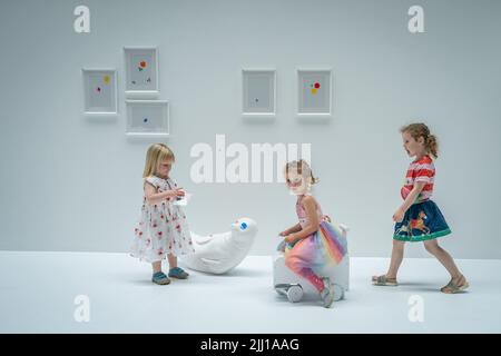 Les enfants appliquent les premiers autocollants au travail interactif de Yayoi Kusama la salle d'oblitération du Tate Modern à Londres, qui commence comme un appartement blanc vierge rempli de tout mobilier blanc. Les visiteurs reçoivent une feuille d'autocollants colorés à leur entrée pour transformer l'installation en une mer de couleur. Date de la photo: Vendredi 22 juillet 2022. Banque D'Images