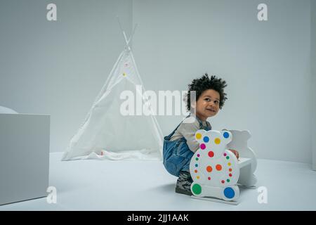 Un enfant applique certains des premiers autocollants au travail interactif de Yayoi Kusama la salle obliteration au Tate Modern de Londres, qui commence comme un appartement blanc vierge rempli de tout mobilier blanc. Les visiteurs reçoivent une feuille d'autocollants colorés à leur entrée pour transformer l'installation en une mer de couleur. Date de la photo: Vendredi 22 juillet 2022. Banque D'Images