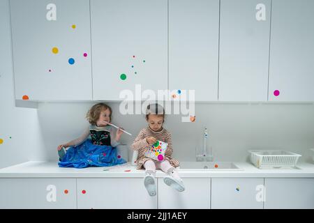 Les enfants appliquent les premiers autocollants au travail interactif de Yayoi Kusama la salle d'oblitération du Tate Modern à Londres, qui commence comme un appartement blanc vierge rempli de tout mobilier blanc. Les visiteurs reçoivent une feuille d'autocollants colorés à leur entrée pour transformer l'installation en une mer de couleur. Date de la photo: Vendredi 22 juillet 2022. Banque D'Images