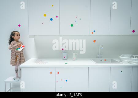 Un enfant applique certains des premiers autocollants au travail interactif de Yayoi Kusama la salle obliteration au Tate Modern de Londres, qui commence comme un appartement blanc vierge rempli de tout mobilier blanc. Les visiteurs reçoivent une feuille d'autocollants colorés à leur entrée pour transformer l'installation en une mer de couleur. Date de la photo: Vendredi 22 juillet 2022. Banque D'Images