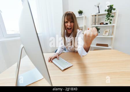 Une femme d'affaires blonde méchante en colère hurlant devant ses subordonnés en se secouant le poing devant la caméra, assis sur son lieu de travail dans un bureau moderne. Le directeur irrité travaille sur Banque D'Images