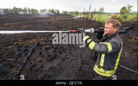 Sassenburg, Allemagne. 22nd juillet 2022. Un pompier éteint un incendie dans la Grande Moor dans le district de Gifhorn. Jeudi, un incendie avait éclaté dans la lande sur une zone d'environ 35 terrains de football. Selon le service des incendies, les travaux d'extinction devraient durer plusieurs jours. Credit: Julian Stratenschulte/dpa/Alay Live News Banque D'Images