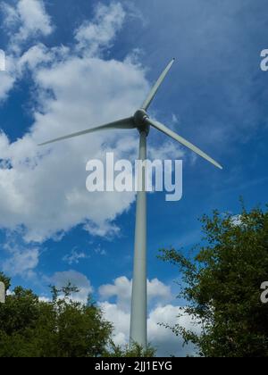 Une grande éolienne à Marston Moretaine, très éclairée et vue de dessous, contre un ciel bleu estival avec des nuages de laine de coton. Banque D'Images