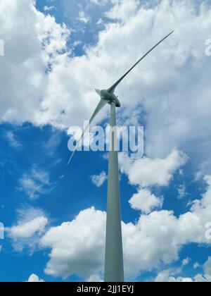 Une grande éolienne à Marston Moretaine, très éclairée et vue de dessous, contre un ciel bleu estival avec des nuages de laine de coton. Banque D'Images