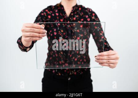 Femme d'affaires tenant un verre rectangulaire tout en affichant des données importantes. Femme portant un T-shirt à motif fleuri montrant une bannière transparente tout en faisant de la publicité sur le Banque D'Images