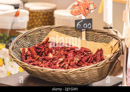 Tomates rouges séchées au soleil dans un panier en osier avec prix dans un marché de la rue à Bari, gros plan. Les tomates mûres perdent la plus grande partie de leur eau Banque D'Images